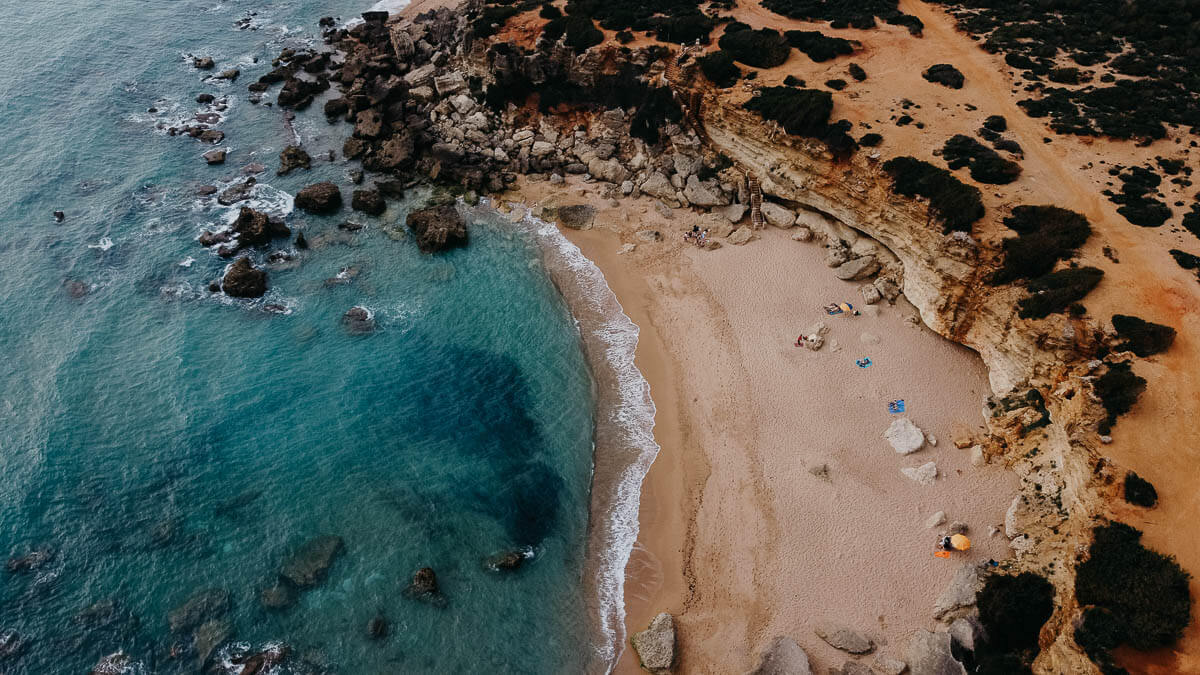 An aerial view of Calas de Roche shows a secluded cove with a sandy beach.