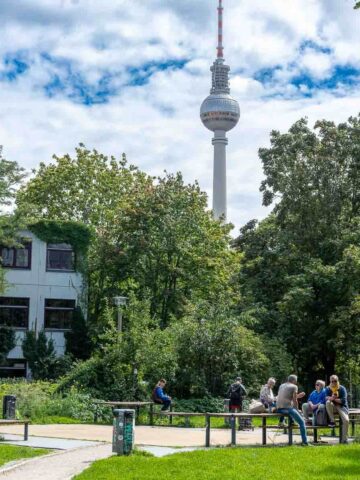 Park with TV Tower in Background: The Berlin TV Tower visible from a park filled with green trees.