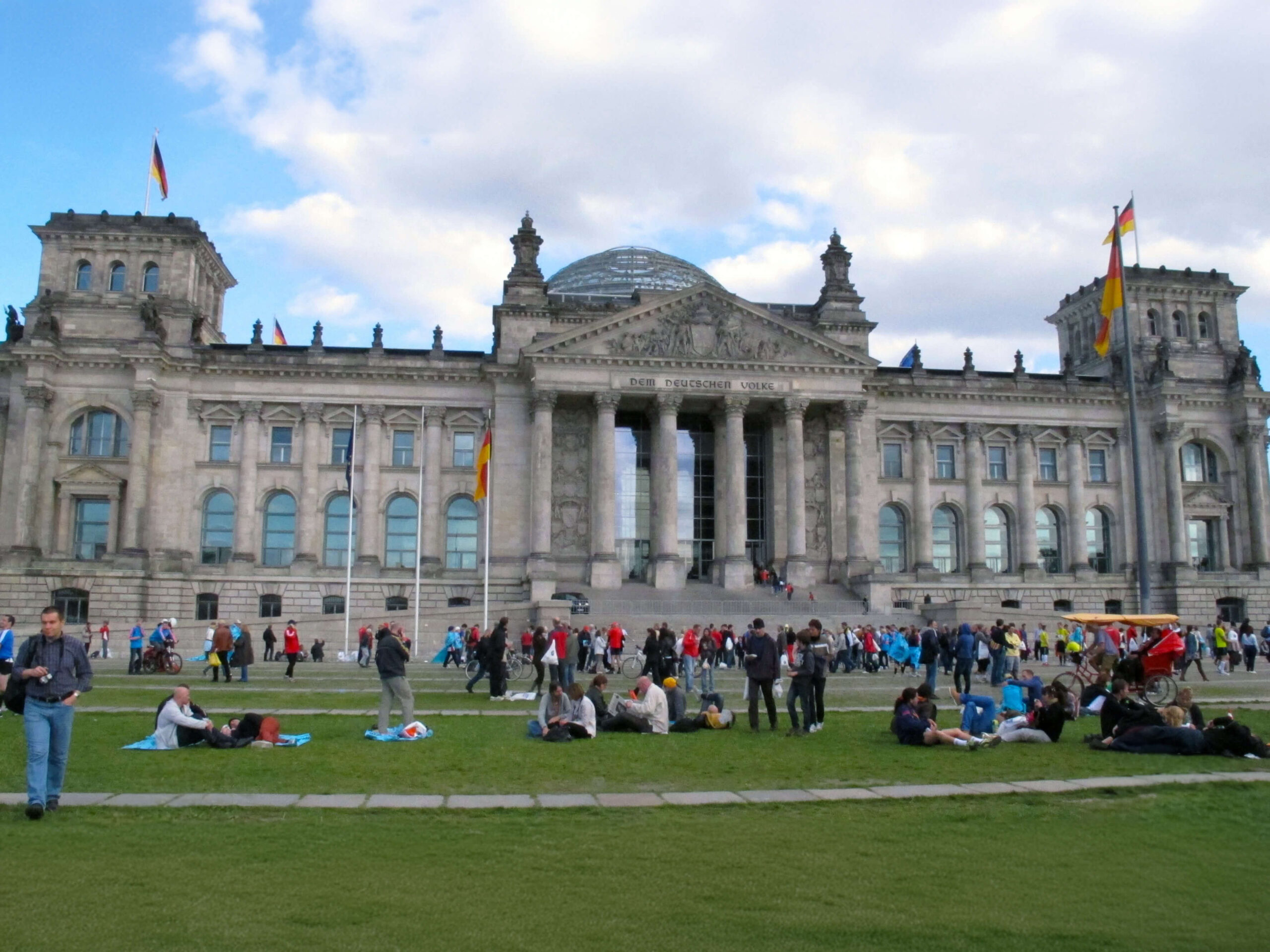 People relaxing and having picnics on the lawn in front of the historic Reichstag building in Berlin next to the Tiertgarten.