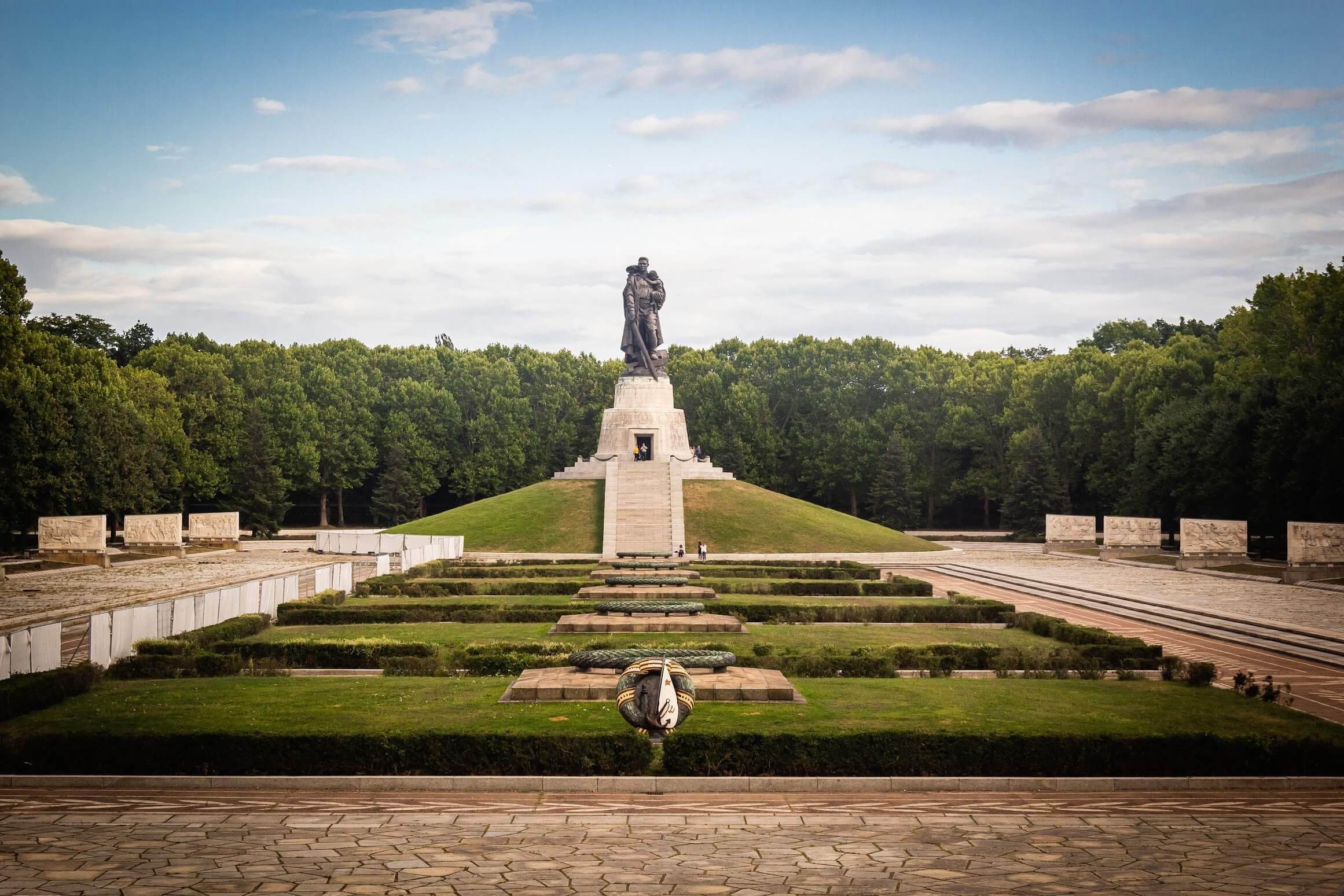 Statue in the Park: A large statue in a beautifully landscaped park with green lawns and trees.