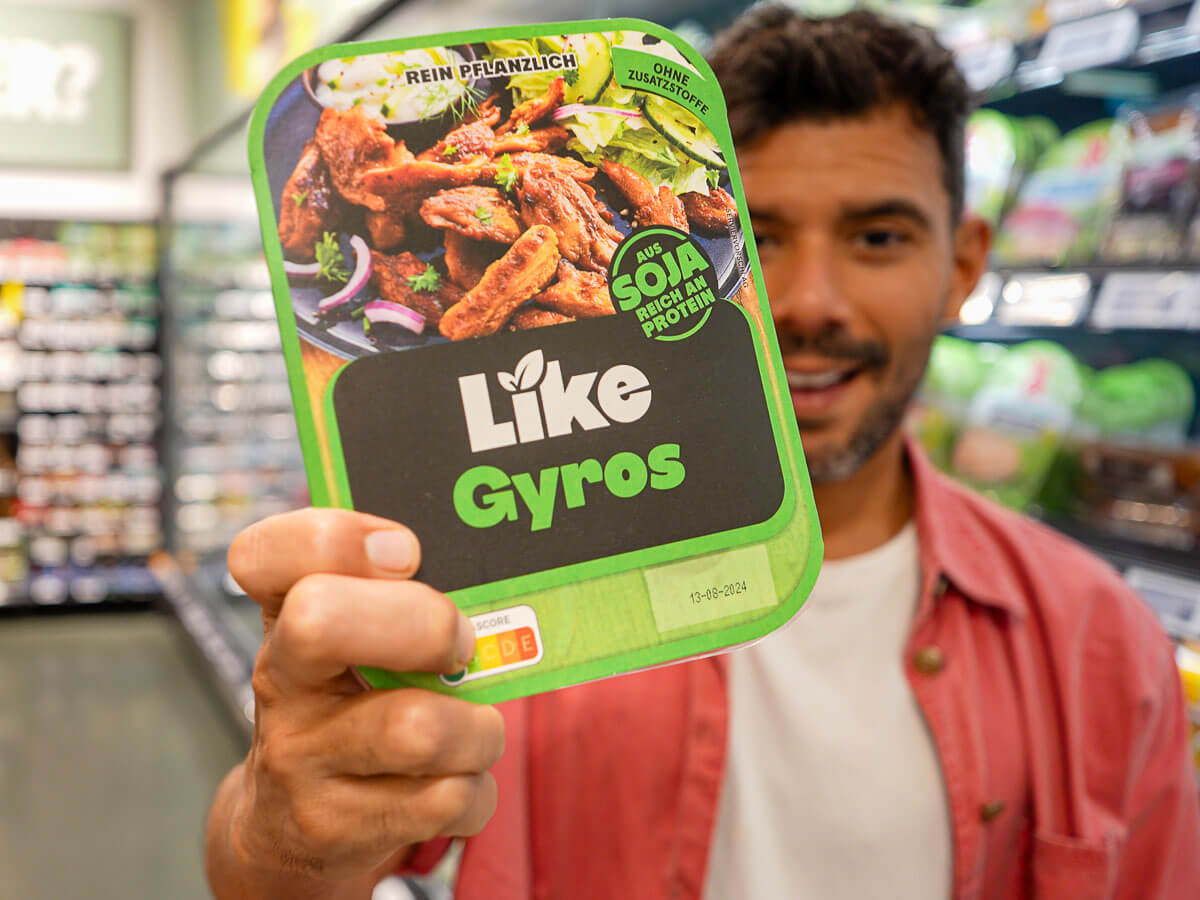 A person holding up a package of vegan gyros with a smile, showcasing it to the camera.