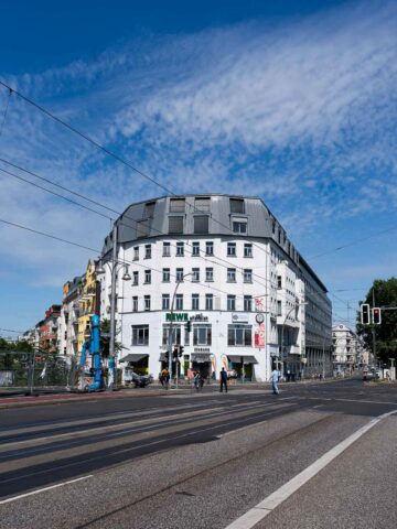 The exterior of a modern building in Berlin, possibly the REWE Plant-Based store, with a clear sky overhead.