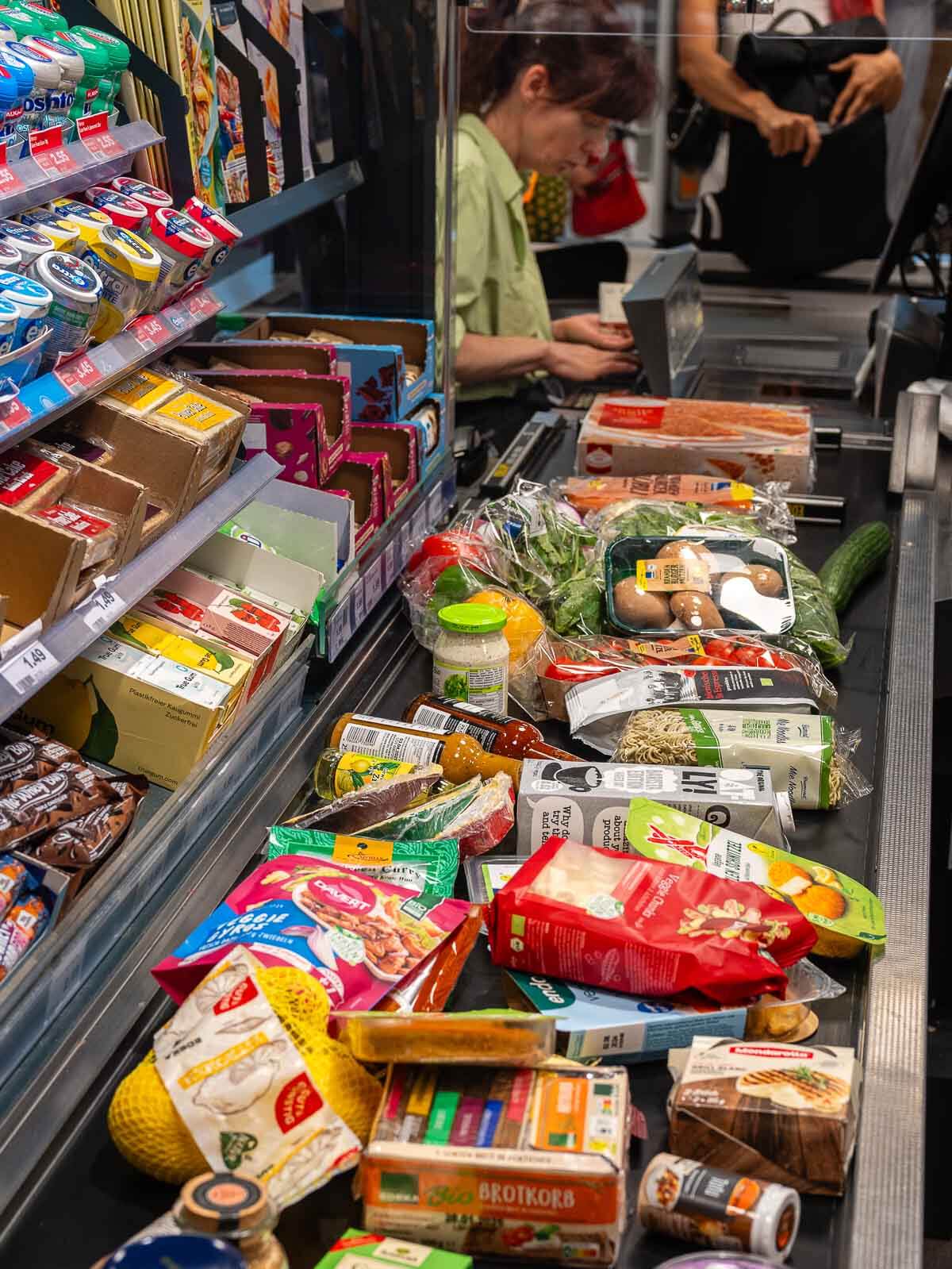 A grocery cart filled with an assortment of vegan products, including frozen items, snacks, and fresh produce.