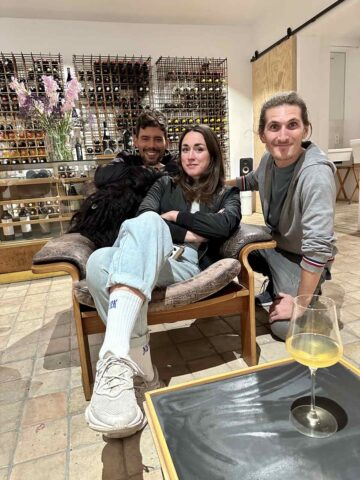 A group of friends relaxing in a cozy setting, seated on a comfortable chair inside a Berlin winery, enjoying each other’s company with a glass of wine.