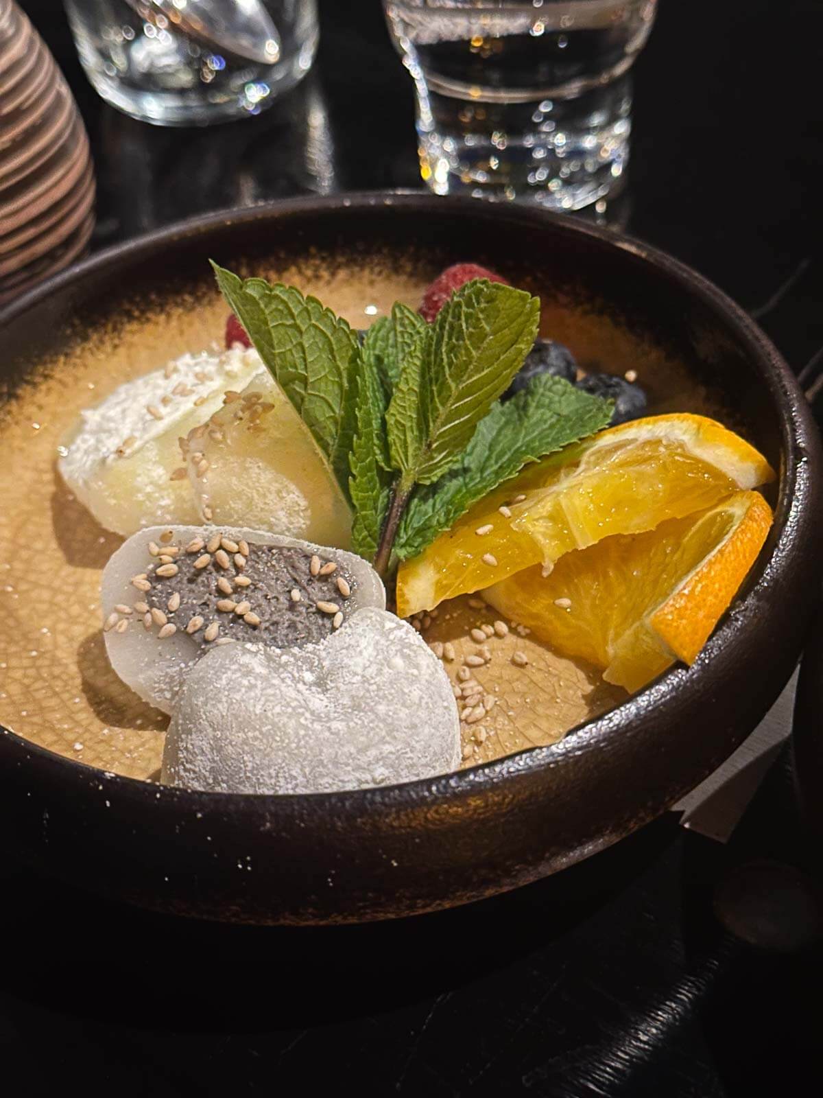 A bowl of vegan mochi garnished with fresh orange slices and mint leaves in a Berlin restaurant.