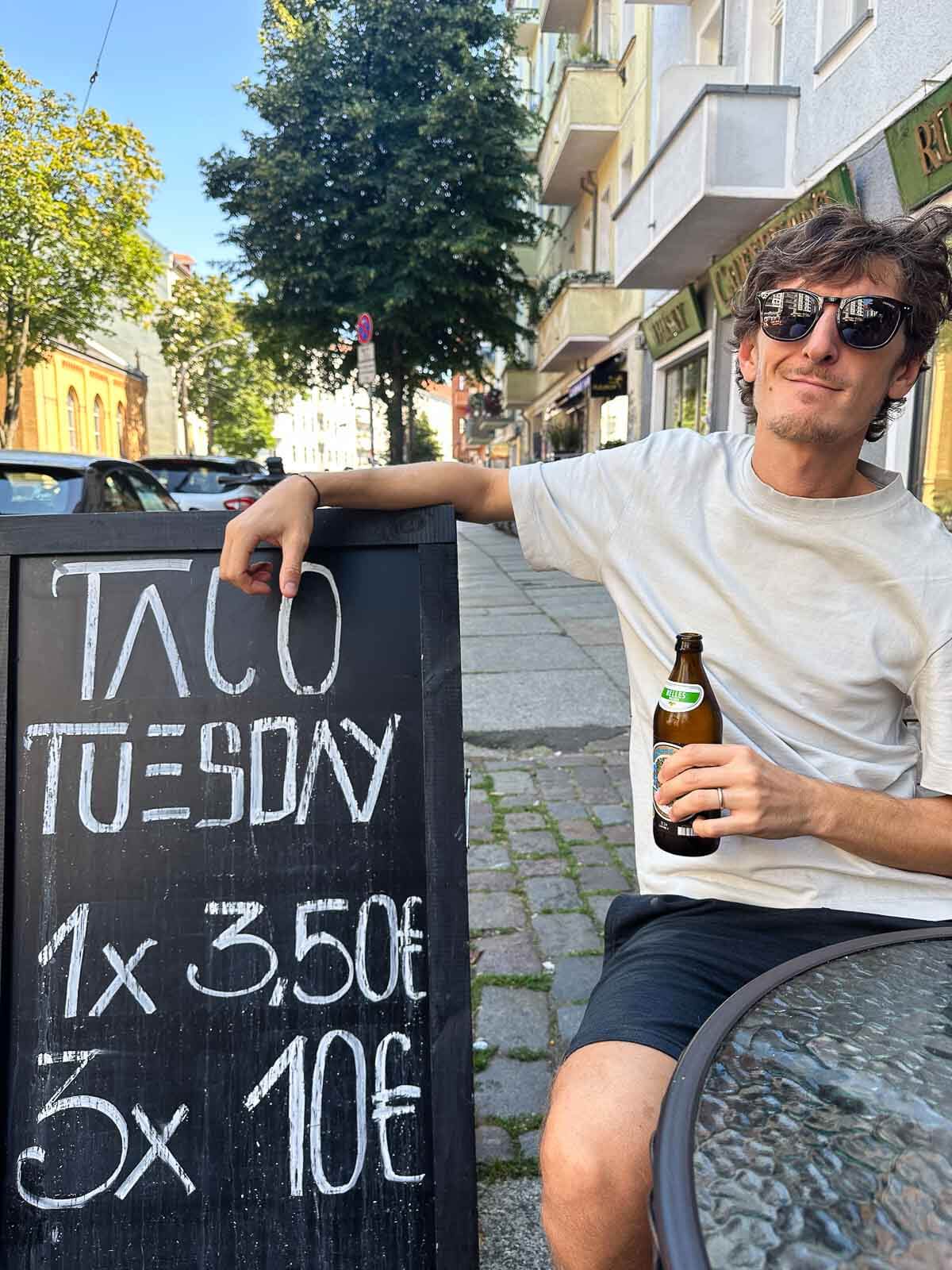 A person enjoying a hearty vegan meal with a drink at an outdoor restaurant in Berlin.