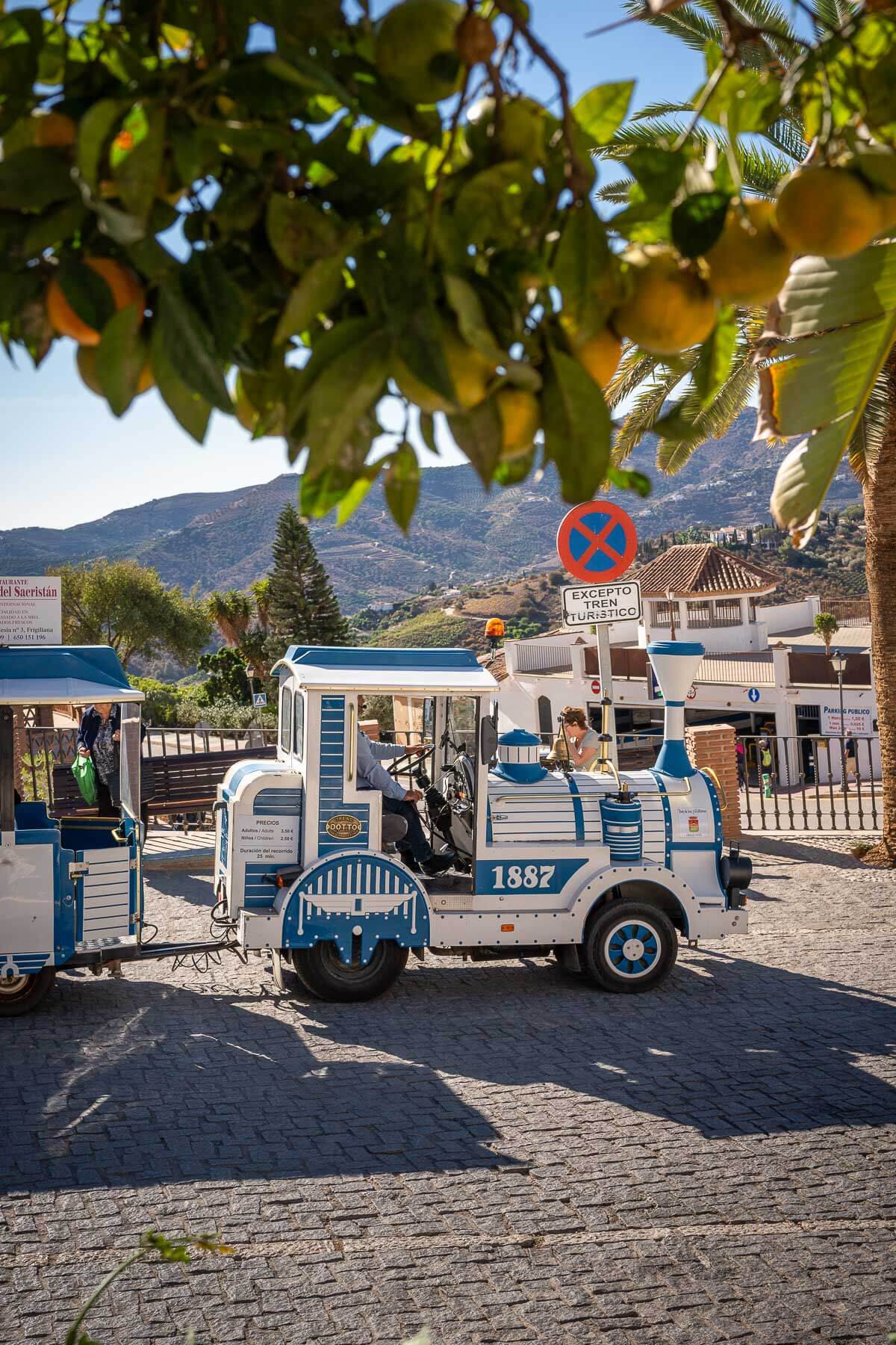 A small tourist train in Frigiliana's town square, offering rides through the village's narrow, scenic streets.