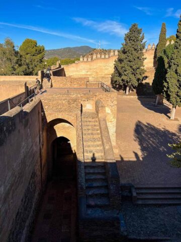 The ancient steps of Málaga's Gibralfaro Castle, offering a stunning view of the city and surrounding landscape under a clear blue sky.