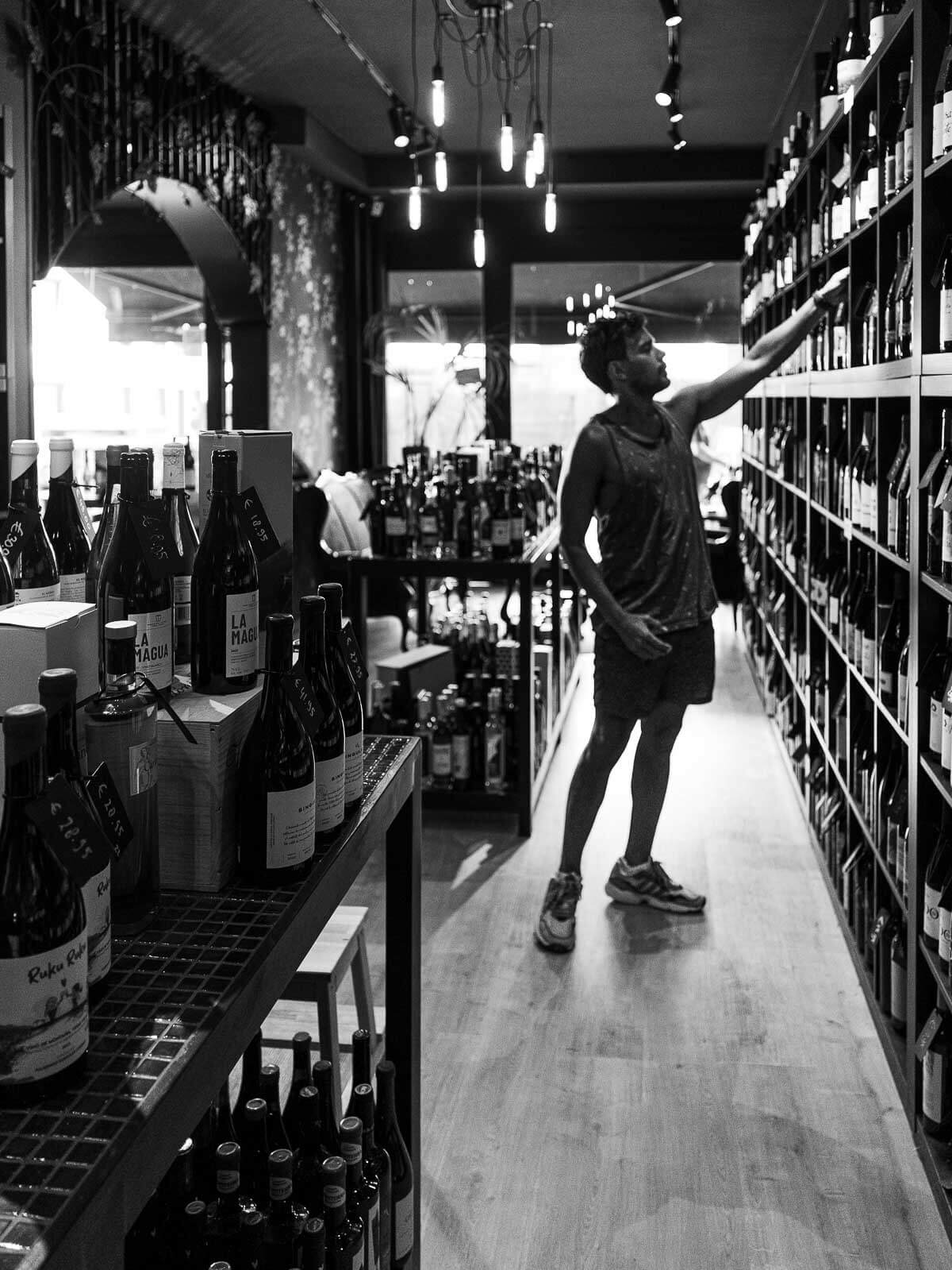 Customer browsing wines at Vinoteca Con Pasión - A black-and-white image of a person exploring wine shelves.