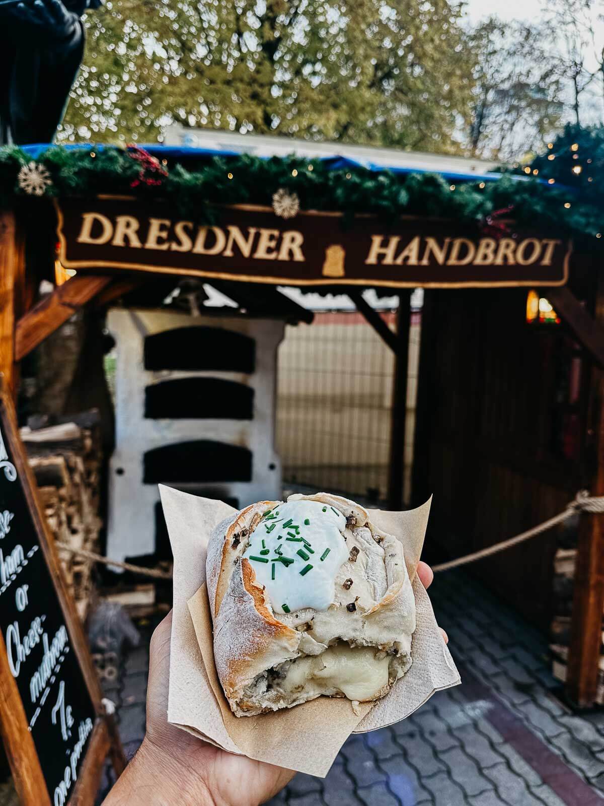 A freshly baked handbrot filled with cheese and topped with herbs, a popular snack at Berlin markets.