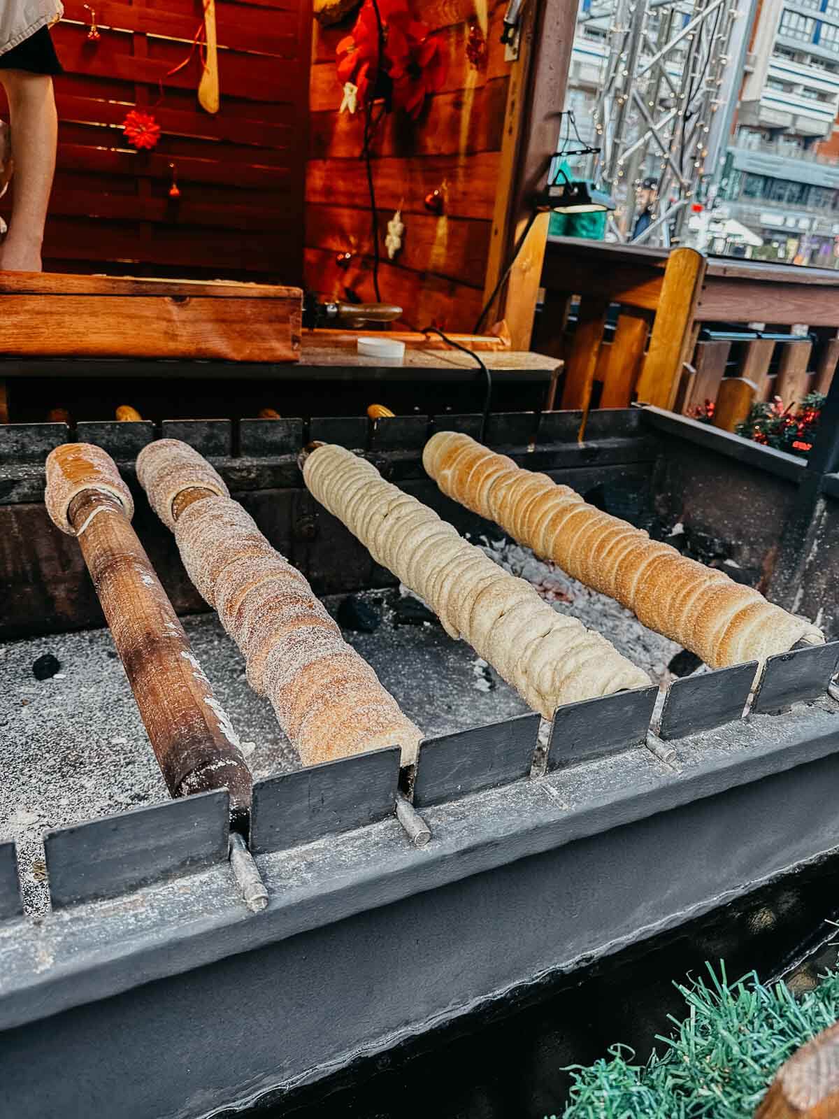 Traditional chimney cakes being cooked over an open fire at a Berlin market stall.