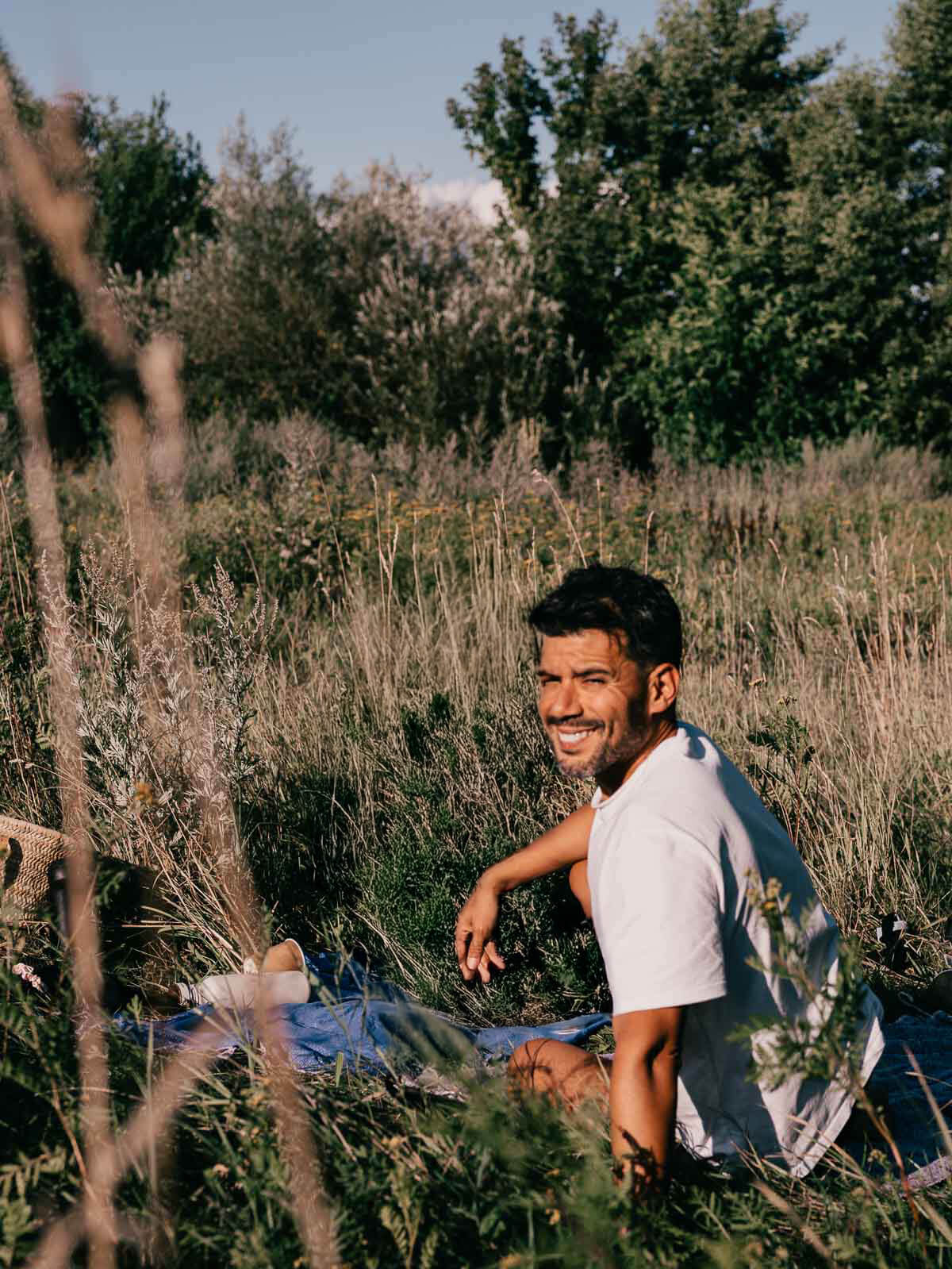 A man sitting and relaxing in a grassy area, soaking up the sun in a serene Berlin park.