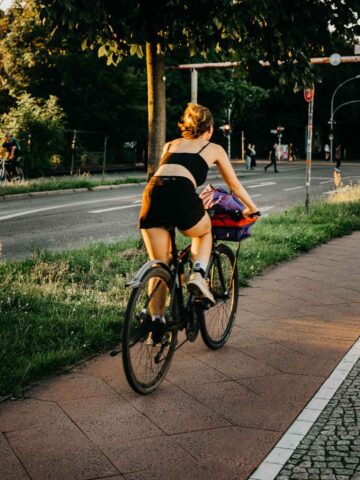 A cyclist enjoying a ride along a tree-lined path on a sunny day in Berlin.