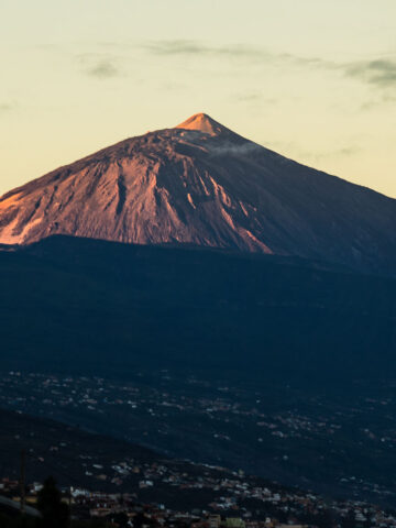 A slightly darker view of Mount Teide at dusk, with soft clouds in the background and shadowed slopes.