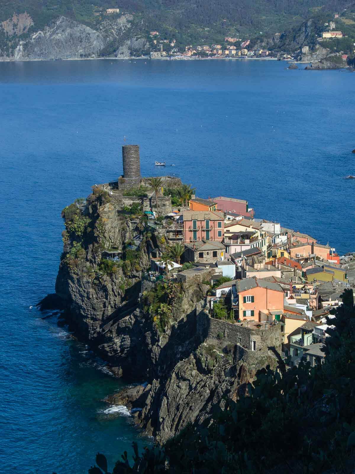 Aerial view of Vernazza with terraced hills, colorful houses, and the blue Ligurian Sea stretching into the horizon.”