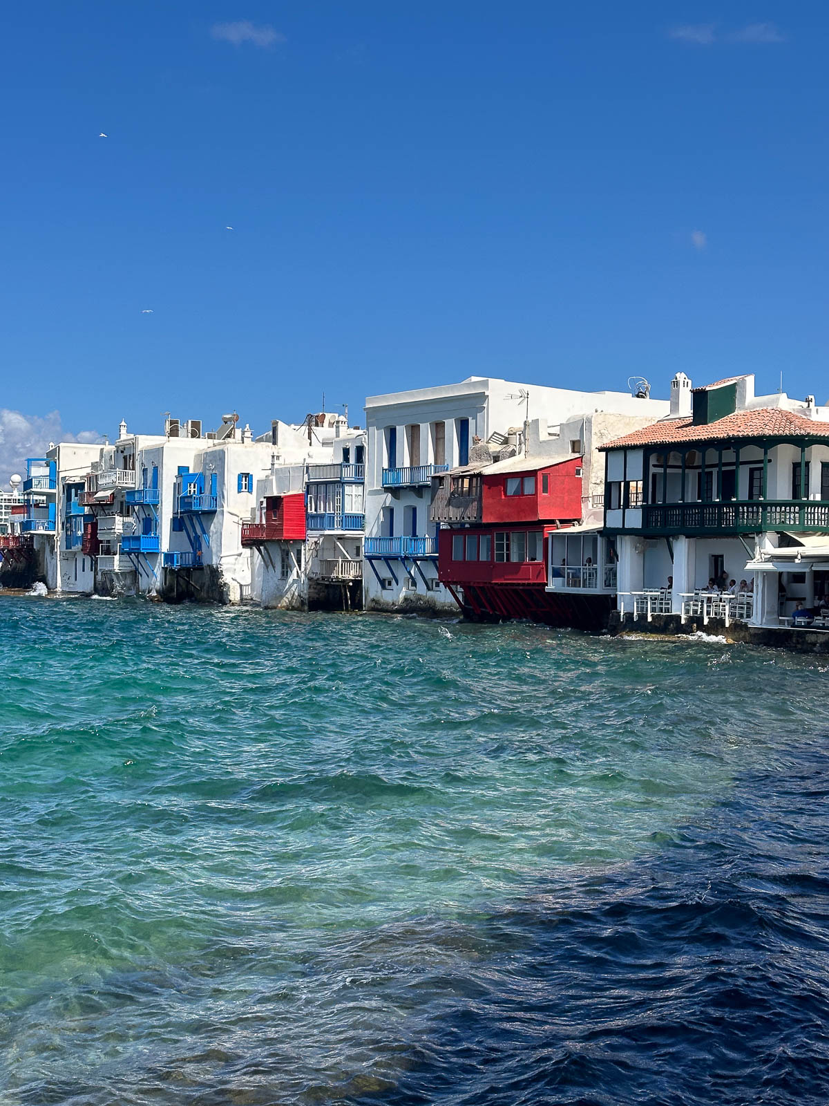Colorful houses of Little Venice in Mykonos, perched right above the sparkling Aegean Sea.