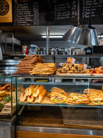 Bakery window in Mykonos filled with sweet and savory pastries.