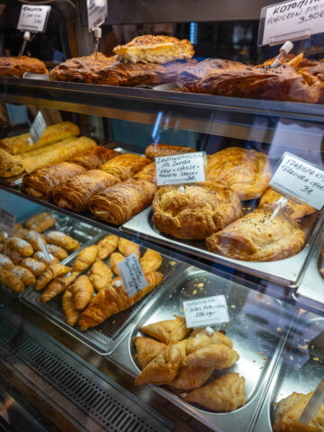 Bakery window in Mykonos filled with sweet and savory pastries.
