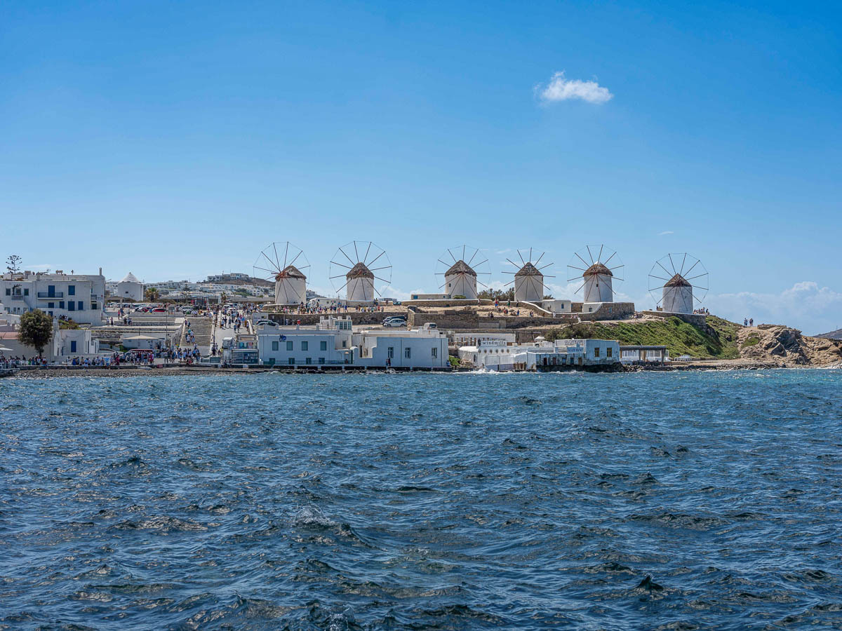 Historic windmills of Mykonos standing tall against the blue sky.