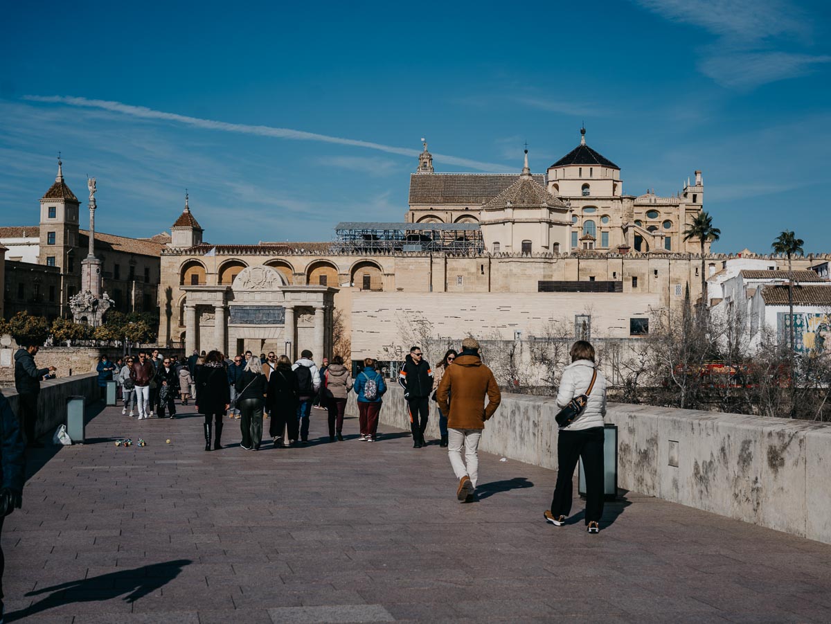Tourists walking the Roman Bridge with the Mezquita-Catedral in the background.